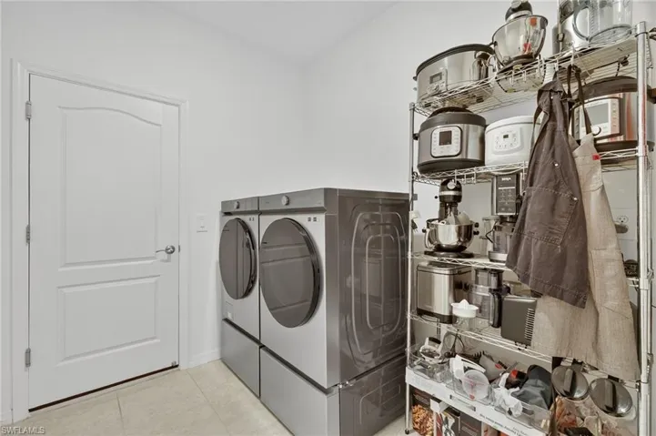 Bedroom featuring a tray ceiling, light tile patterned floors, a ceiling fan, and ensuite bathroom