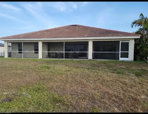 Back of property featuring a yard, a sunroom, and a tiled roof
