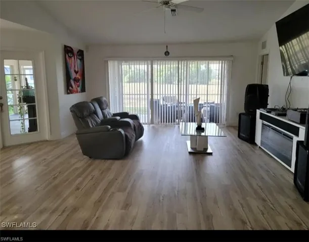 Living area with light wood-style flooring, plenty of natural light, ceiling fan, and vaulted ceiling