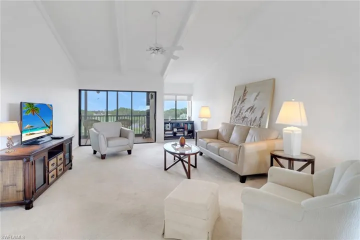 Carpeted living area with ceiling fan and beamed ceiling