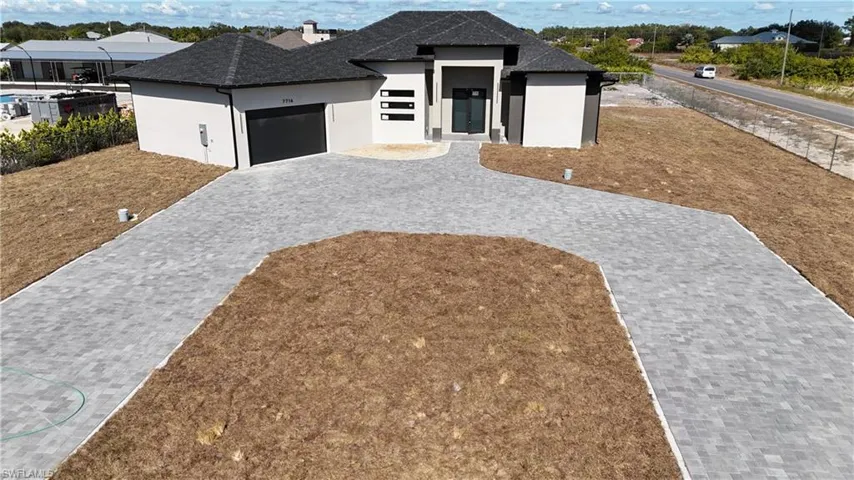 Contemporary house with stucco siding, decorative driveway, an attached garage, a chimney, and a shingled roof