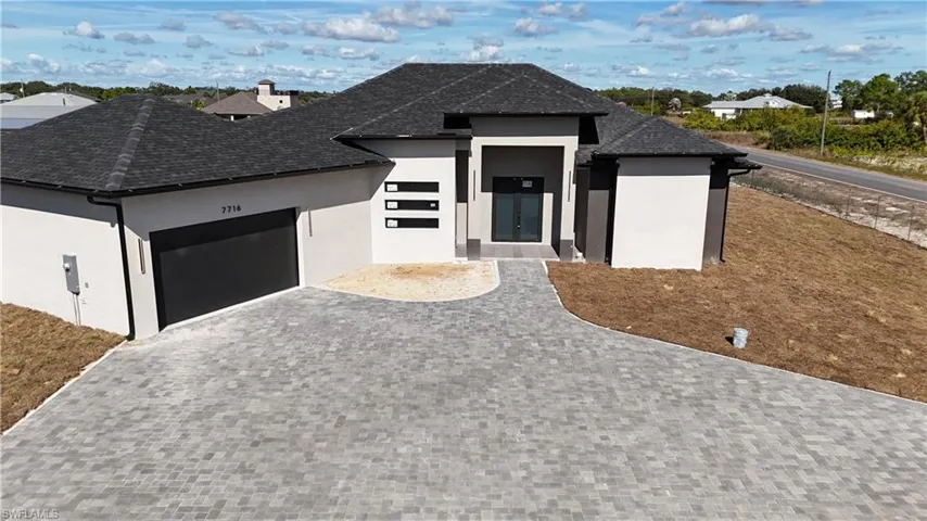 View of front of home featuring a garage, stucco siding, and decorative driveway