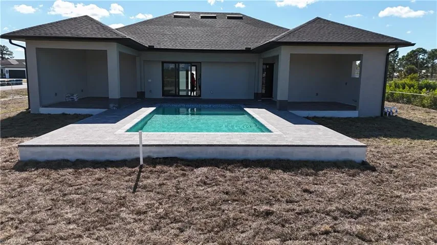Back of property with a patio area, an outdoor pool, a shingled roof, and stucco siding
