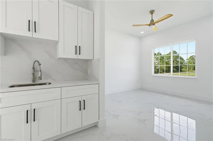 Bar area with white cabinets, light marble finish floors, light stone countertops, decorative backsplash, and recessed lighting