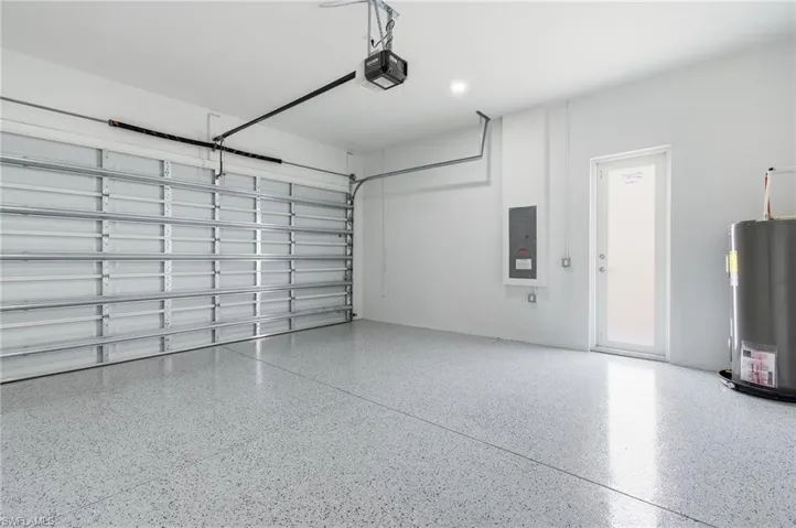 Garage featuring electric panel, water heater, and a garage door opener