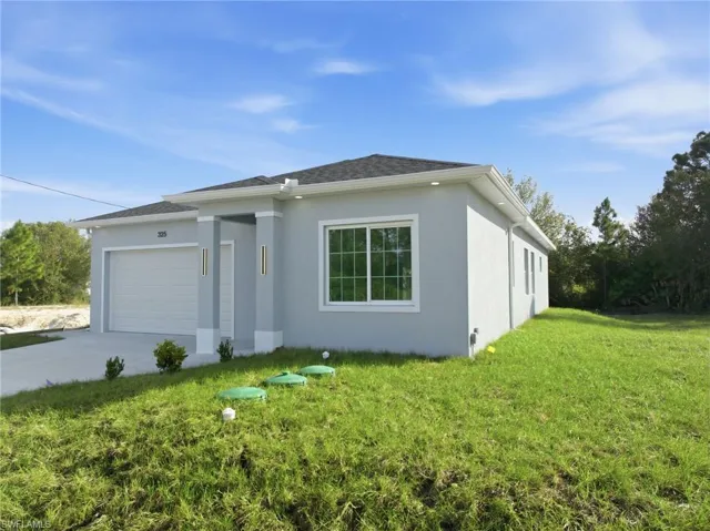 View of front facade featuring a front yard, an attached garage, concrete driveway, and stucco siding