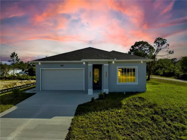 Ranch-style home featuring stucco siding, concrete driveway, a garage, a lawn, and roof with shingles