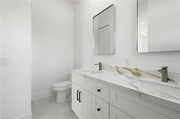 Bathroom featuring light marble finish floors and double vanity
