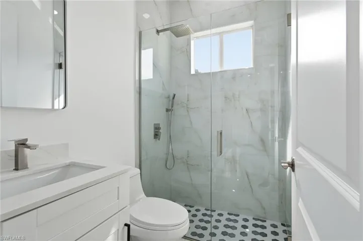 Full bath featuring vanity and a marble finish shower