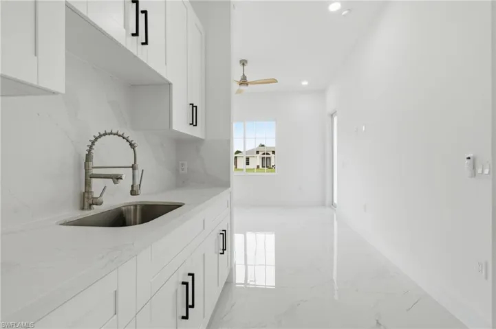 Kitchen with white cabinets, light stone counters, light marble finish flooring, recessed lighting, and tasteful backsplash