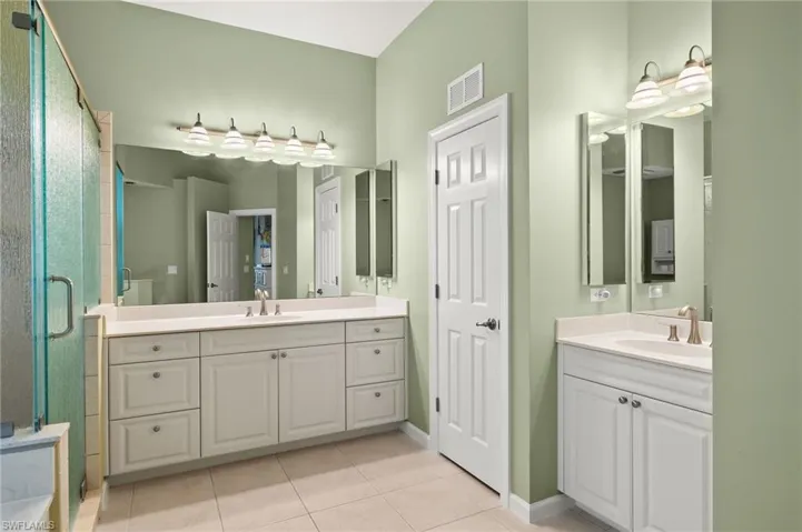 Bathroom with vanity, walk in shower, and tile patterned flooring