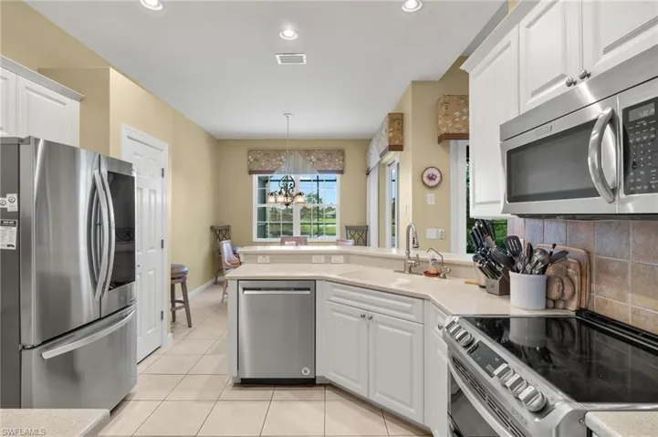 Kitchen with sink, appliances with stainless steel finishes, an inviting chandelier, and white cabinets