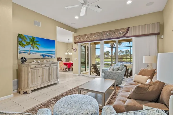 Living room featuring ceiling fan with notable chandelier and light tile patterned floors
