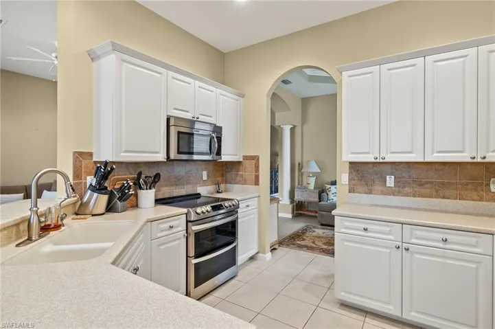 Kitchen featuring appliances with stainless steel finishes, sink, light tile patterned flooring, and white cabinets