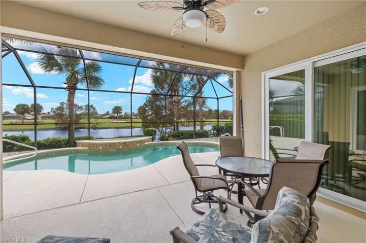 View of swimming pool with a lanai, a water view, ceiling fan, and a patio area