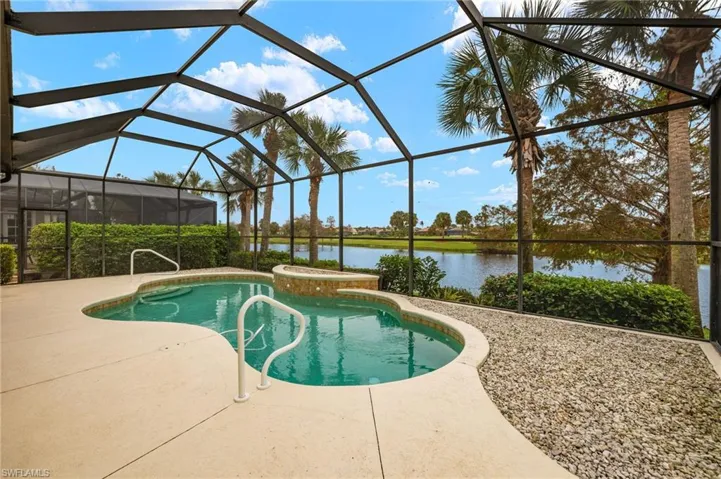 View of pool featuring glass enclosure, a water view, and a patio area