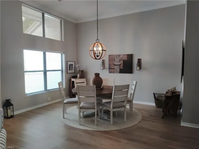 Dining room featuring wood finished floors, hanging lights, crown molding, and a high ceiling