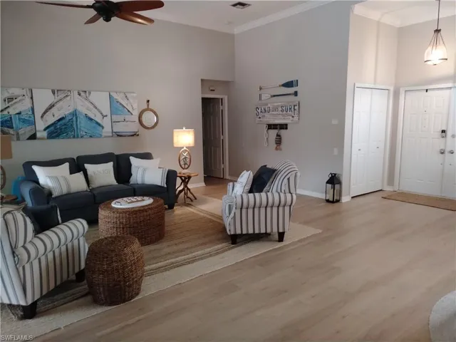 Living area with wood finished floors, a high ceiling, ceiling fan, and ornamental molding