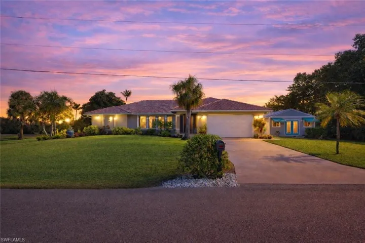 Ranch-style house with driveway, a front yard, a garage, and stucco siding