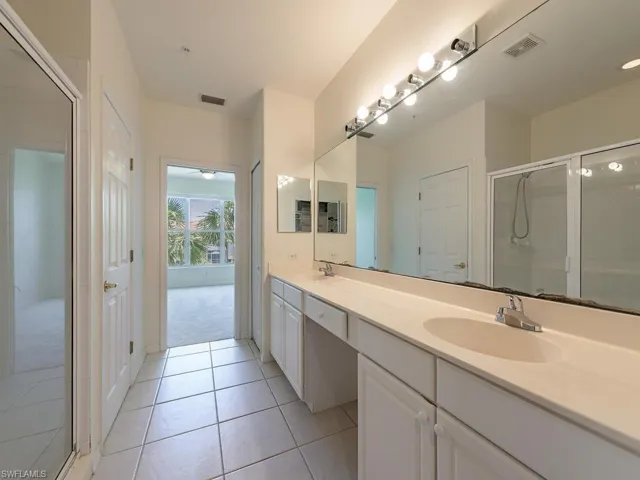 Bathroom featuring a shower with shower door, tile patterned floors, and double sink vanity