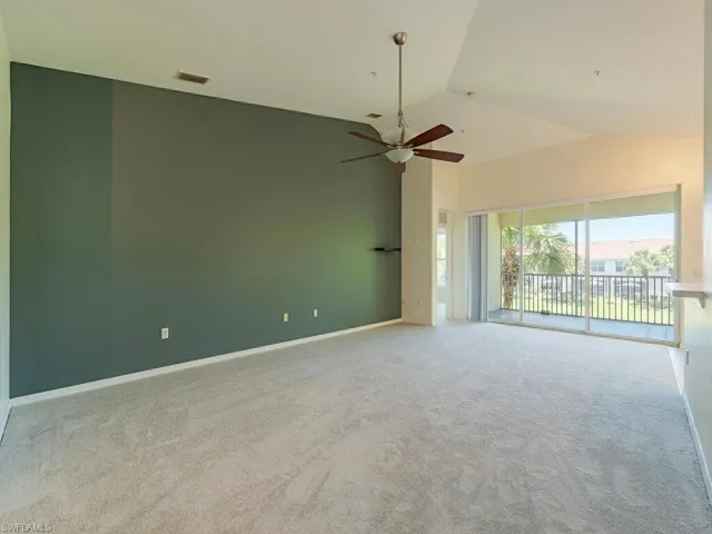 Carpeted spare room featuring high vaulted ceiling and ceiling fan