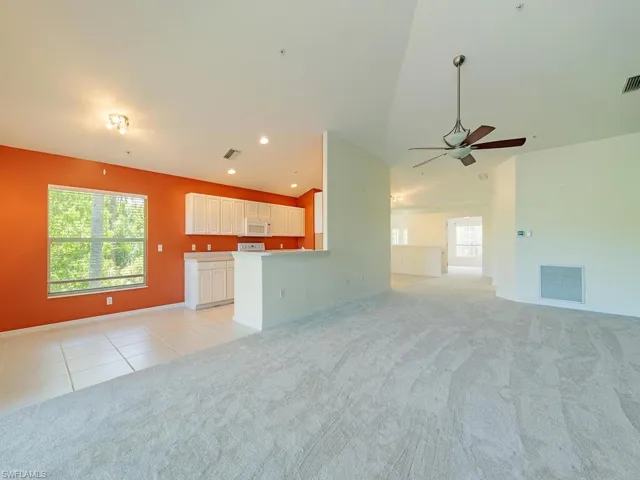 Unfurnished living room with light carpet, ceiling fan, and lofted ceiling
