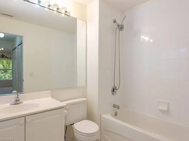 Full bathroom with toilet, tiled shower / bath combo, and vanity