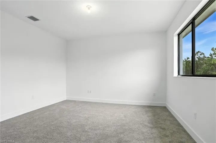 Unfurnished room featuring light carpet and baseboards