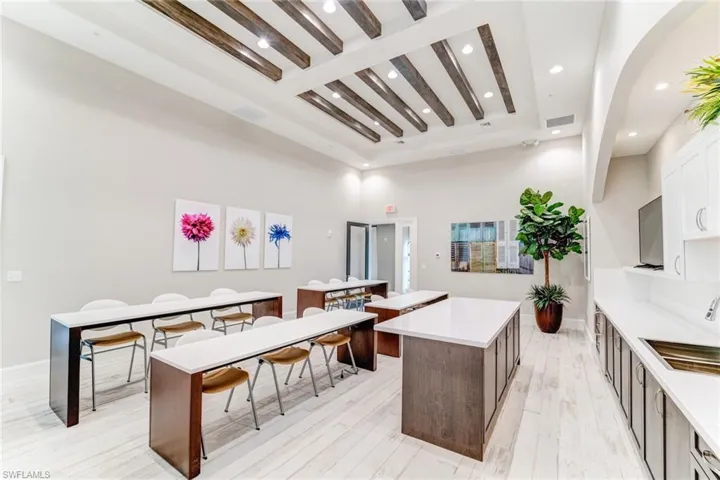 Kitchen featuring light wood-style flooring, light stone counters, beamed ceiling, recessed lighting, and a kitchen breakfast bar
