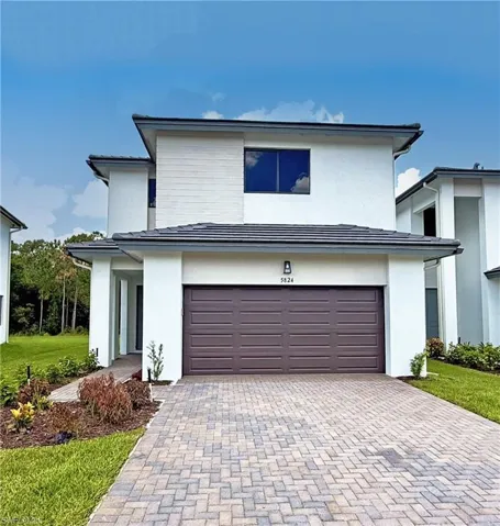 View of front of property featuring decorative driveway, stucco siding, and a garage