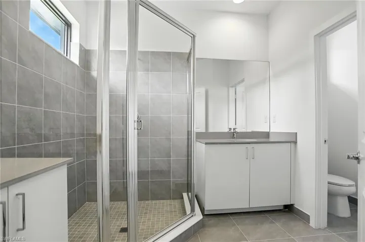 Full bath with vanity, a stall shower, and light tile patterned floors