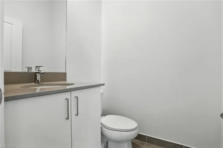Half bath with vanity and dark tile patterned flooring