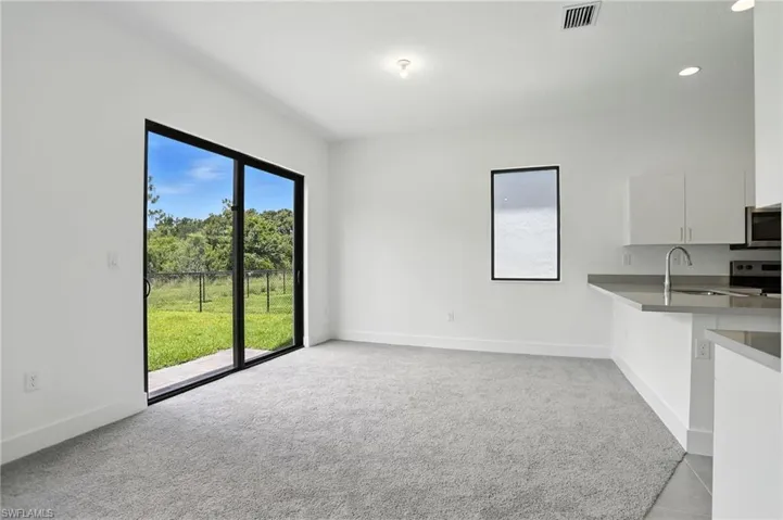 Unfurnished living room with light colored carpet and recessed lighting