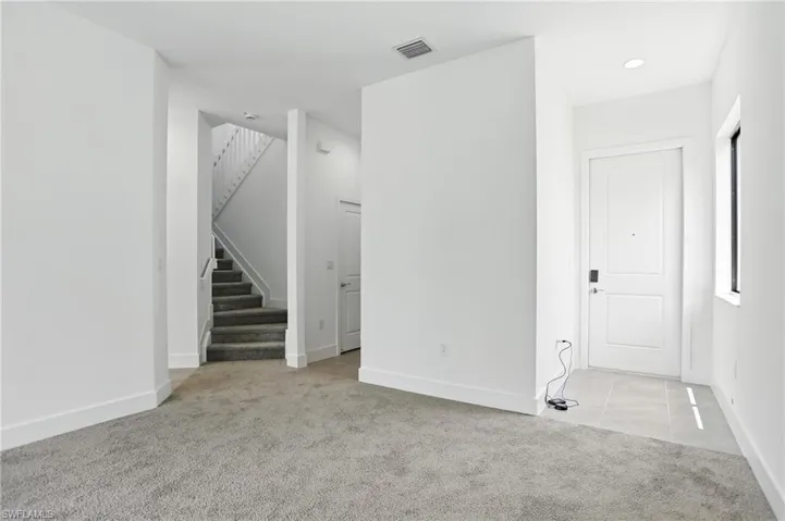 Unfurnished room featuring light colored carpet, stairs, light tile patterned flooring, and recessed lighting