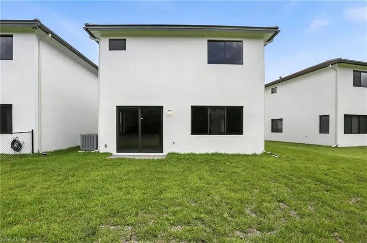Back of property with a lawn and stucco siding