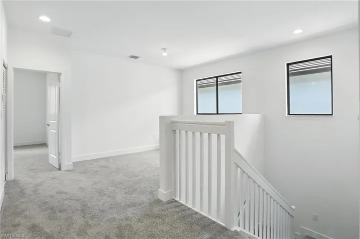 Hall with recessed lighting, an upstairs landing, and light colored carpet
