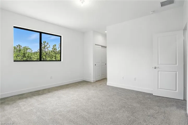 Unfurnished bedroom with light carpet and a closet