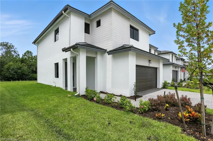 View of property exterior with stucco siding, a yard, decorative driveway, and an attached garage