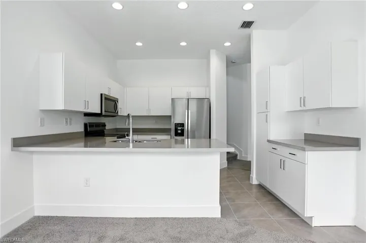 Kitchen featuring stainless steel appliances, white cabinetry, a peninsula, recessed lighting, and light tile patterned flooring