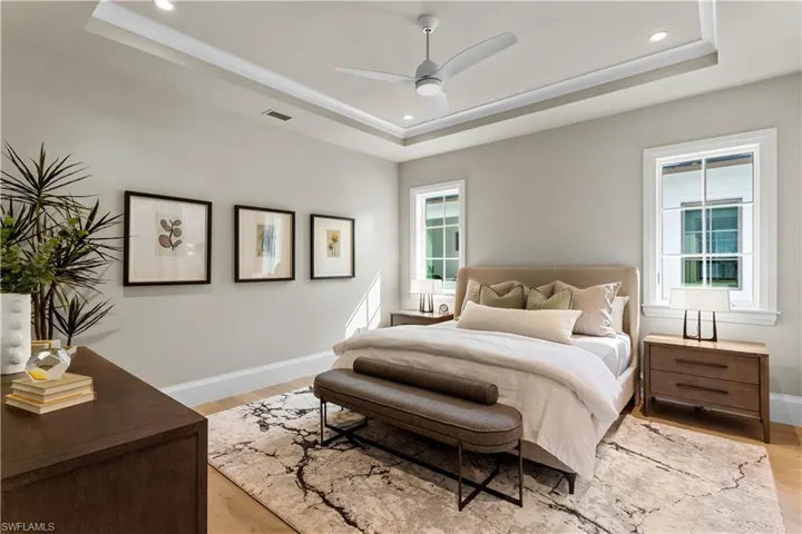 Bedroom featuring a raised ceiling, light wood-type flooring, baseboards, and recessed lighting