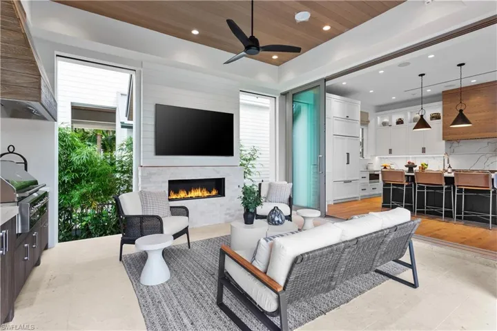 Living room featuring a lit fireplace, healthy amount of natural light, a ceiling fan, wooden ceiling, and recessed lighting