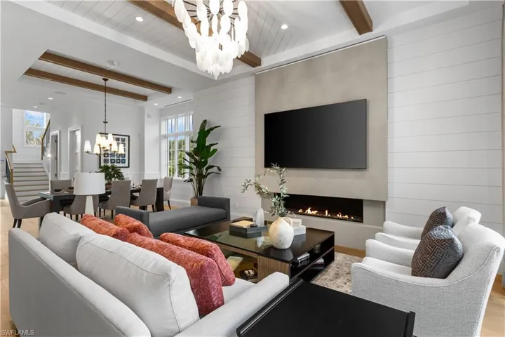 Living area with a chandelier, light wood finished floors, recessed lighting, a warm lit fireplace, and wooden walls