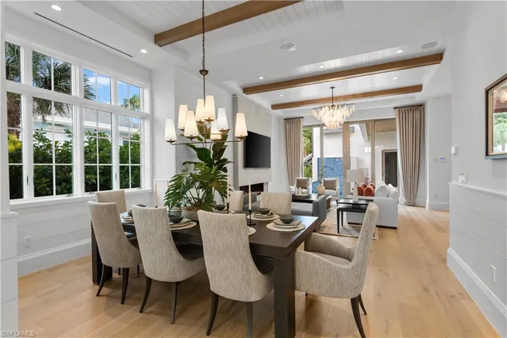 Dining area with a chandelier, beam ceiling, healthy amount of natural light, light wood-style flooring, and recessed lighting