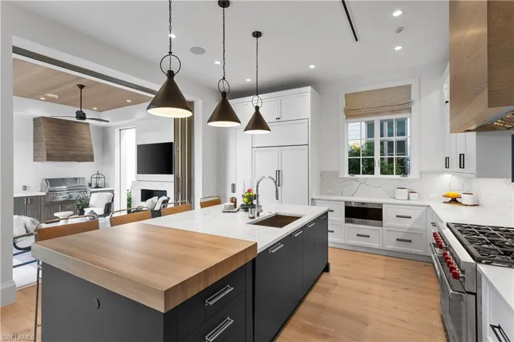 Kitchen with a sink, high end appliances, open floor plan, premium range hood, and dark cabinets
