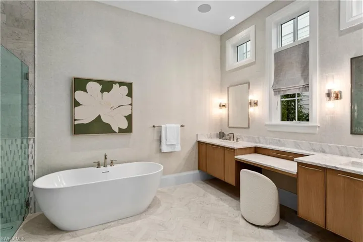 Full bathroom featuring a soaking tub, vanity, a stall shower, baseboards, and a high ceiling