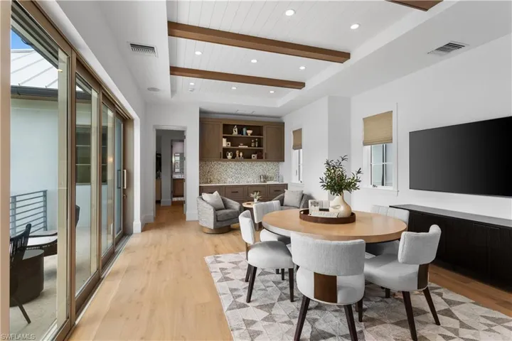 Dining room featuring light wood-style flooring, plenty of natural light, recessed lighting, wooden ceiling with exposed beams, and a tray ceiling
