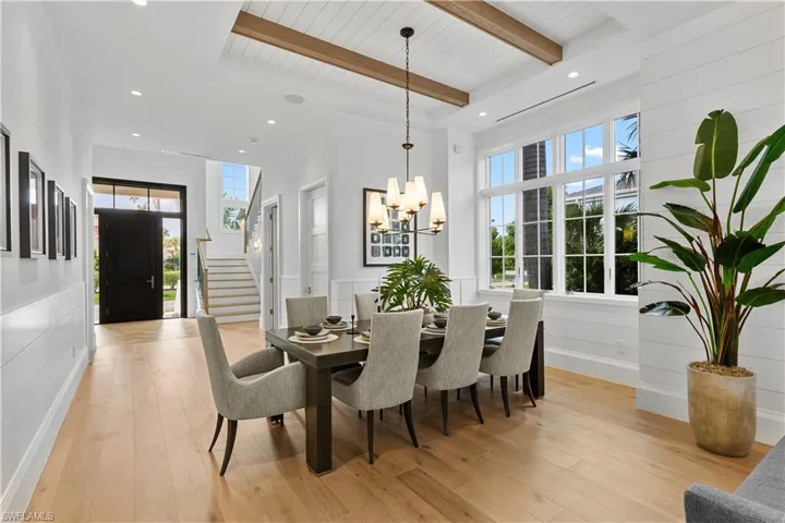 Dining area featuring a chandelier, beam ceiling, stairway, light wood-style flooring, and plenty of natural light