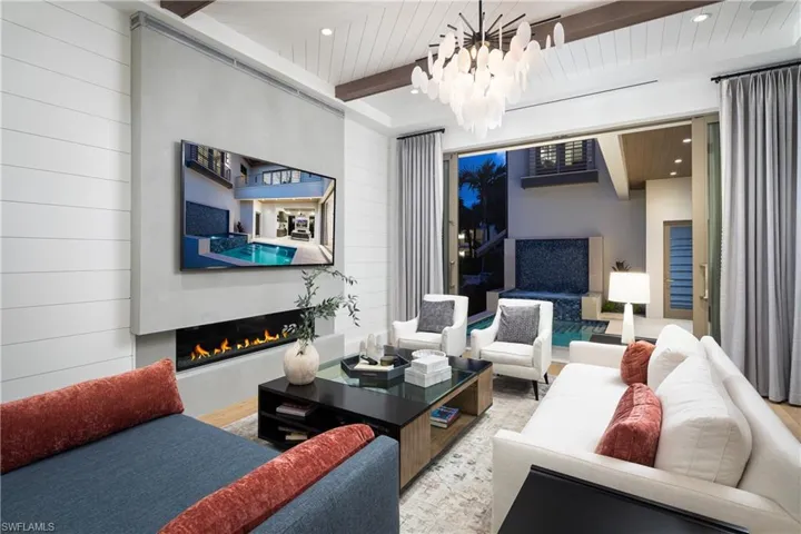 Living area with a warm lit fireplace, wood finished floors, a chandelier, recessed lighting, and wooden walls