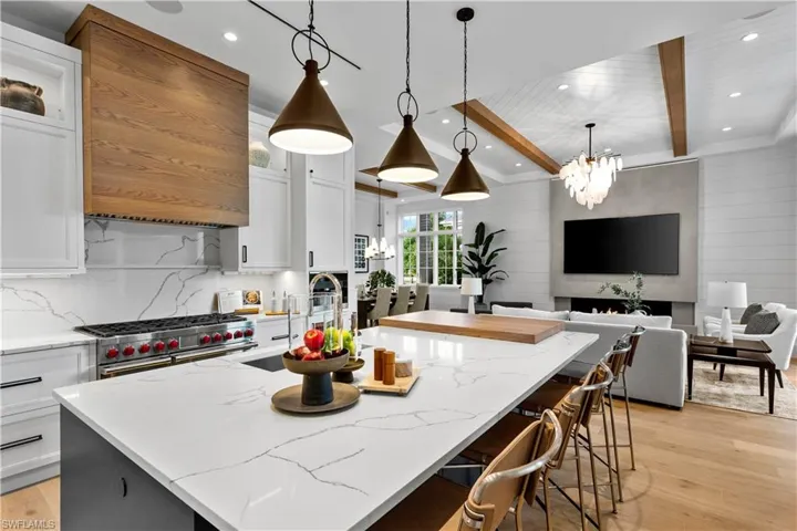 Kitchen featuring high end stainless steel range oven, a large island with sink, light wood-type flooring, a chandelier, and white cabinets