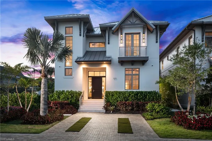View of front of home with a balcony, a standing seam roof, stucco siding, and metal roof